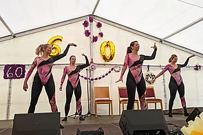 4 Frauen in Kostümen auf einer Bühne beim Tanzen auf dem 60-Jahre Sommerfest des Hufeland-hauses