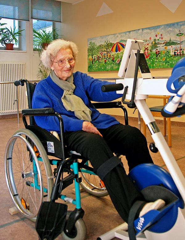 Bewohnerin bei der Nutzung eines 'MotoMed' (motorunterstütztes Bewegungstherapiegerät für die Beine)