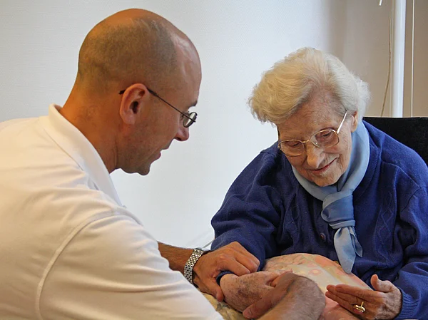 Bewohnerin mit einem Physiotherapeuten bei der Therapie der Hände