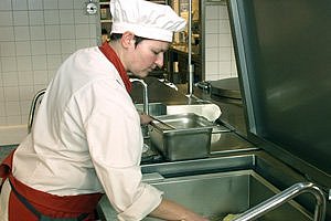 Köchin in der Küche des Hufeland-Hauses, beim Frittieren – das Bild verlinkt auf die Seite des Tagesrestaurants